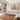 Sturt’s Desert Pea framed canvas artwork in a natural timber frame, displayed above a cream sectional sofa in a bright, neutral living room.